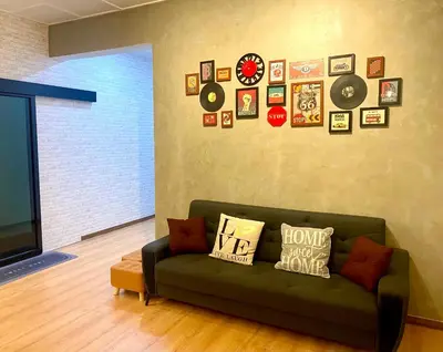 a living room with a green couch and clocks on the wall at comfy 3-bedrooms with family karaoke Max-10pax in Ipoh