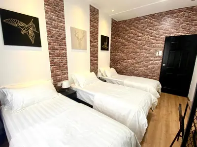 three beds in a room with a brick wall at comfy 3-bedrooms with family karaoke Max-10pax in Ipoh