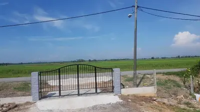 a gate on the side of a road with a field at Room/Homestay NazaDja in Sungai Besar