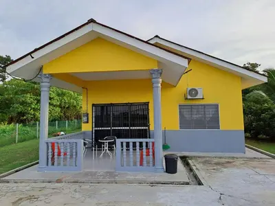a yellow house with a porch and a table at Room/Homestay NazaDja in Sungai Besar