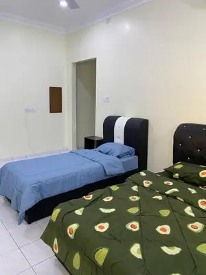 a bedroom with two beds with a green blanket at Room/Homestay NazaDja in Sungai Besar
