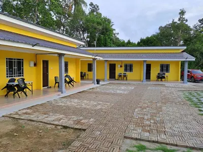 a yellow building with tables and chairs on a patio at Room/Homestay NazaDja in Sungai Besar