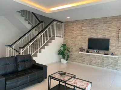 a living room with a black couch and a brick wall at Omari Marina Island Homestay Lumut in Lumut