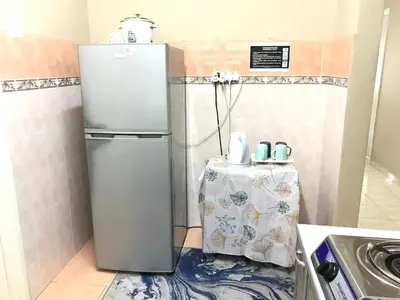 a small kitchen with a refrigerator and a table at Homestay Wafiy Lost World Tambun Ipoh in Ipoh
