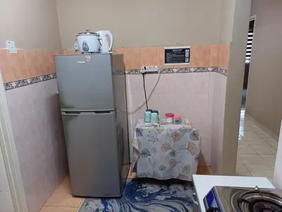 a kitchen with a refrigerator and a table in a room at Homestay Wafiy Lost World Tambun Ipoh in Ipoh