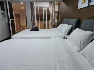 two beds in a hotel room with white sheets and pillows at Maritime Karpal Singh in George Town