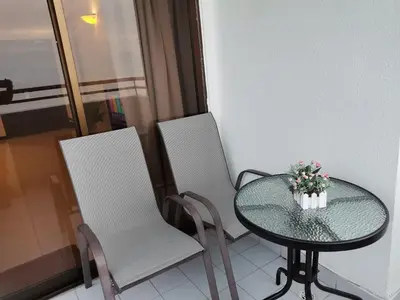 two white chairs and a glass table with a vase of flowers at InvincibleSeaview Batu Ferrighi Sri Sayang \u7121\u6575\u6d77\u666f 2-7 in Batu Ferringhi