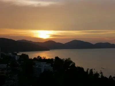 a sunset over a large body of water with mountains at InvincibleSeaview Batu Ferrighi Sri Sayang \u7121\u6575\u6d77\u666f 2-7 in Batu Ferringhi