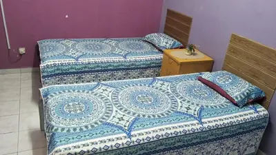 two beds with blue and white sheets in a room at RUMAH INAP BANDAR PERDANA in Sungai Petani
