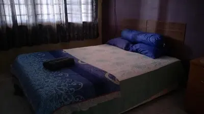a bedroom with a bed with blue pillows on it at RUMAH INAP BANDAR PERDANA in Sungai Petani