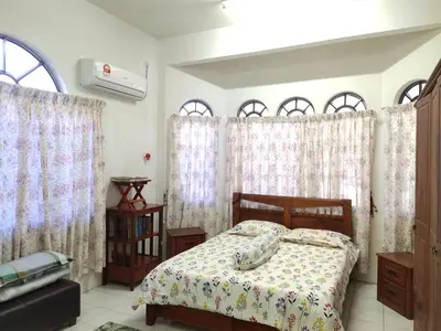 a bedroom with a bed and windows with curtains at Homestay YatiMizi (Bungalow Station 18, Ipoh) in Ipoh