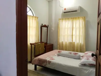 a bedroom with a bed and a mirror and a window at Homestay YatiMizi (Bungalow Station 18, Ipoh) in Ipoh