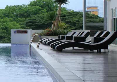 a row of chairs sitting next to a pool of water at H2H - Holland Cottage - Majestic Ipoh - 7pax in Ipoh