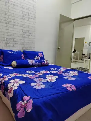 a bed with a blue blanket with flowers on it at Deq Noor Homestay in Cameron Highlands