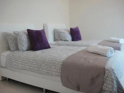 two beds in a room with purple and gray pillows at Shamrock Beach Villas Batu Ferringhi Penang in Batu Ferringhi
