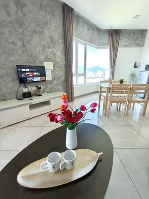 a table with two cups and a vase with flowers at Octagon Premium Ipoh Town Center 2BR 121 by Grab A Stay in Ipoh