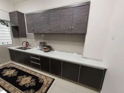 a kitchen with black cabinets and a sink and a rug at HOMESTAY EPOH Meru Raya in Ipoh