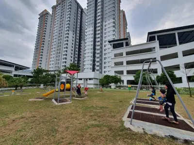 a group of people playing in a park with tall buildings at HOMESTAY EPOH Meru Raya in Ipoh