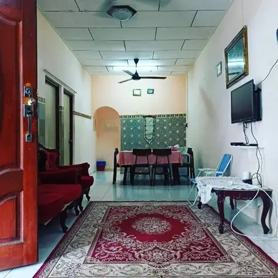 a living room with a table and a red rug at Homestay Musafir 3.0 in Seri Iskandar