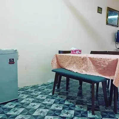 a dining room with a table and a green bench at Homestay Musafir 3.0 in Seri Iskandar