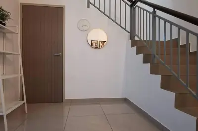 a hallway with stairs and a clock on the wall at The Dandelion Homestay in Baling