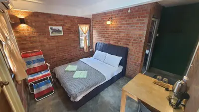 a small bedroom with a bed and a brick wall at Sayang Di Kaki Bukit Homestay Near Icon City Bukit Mertajam in Bukit Mertajam