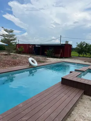 a swimming pool with a wooden deck and a building at HOMESTAY Kampong KOTA AUR Resort with swimming pool, Kepala Batas, SEBERANG PERAI, PENANG -MOTAC registered Awarded ASEAN homestay standard Malaysia AWARD 2023-2028 Only 3 minutes from viral KG AGONG in Kepala Batas