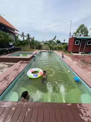 two children playing with a frisbee in a swimming pool at HOMESTAY Kampong KOTA AUR Resort with swimming pool, Kepala Batas, SEBERANG PERAI, PENANG -MOTAC registered Awarded ASEAN homestay standard Malaysia AWARD 2023-2028 Only 3 minutes from viral KG AGONG in Kepala Batas