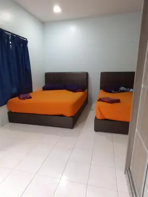 two beds in a room with orange sheets at Kamar Musafir MMS in Ipoh