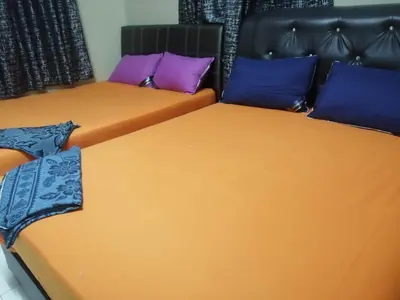 two beds in a room with purple and blue pillows at Kamar Musafir MMS in Ipoh
