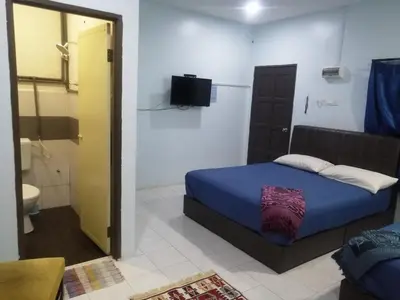 a bedroom with a blue bed and a bathroom at Kamar Musafir MMS in Ipoh