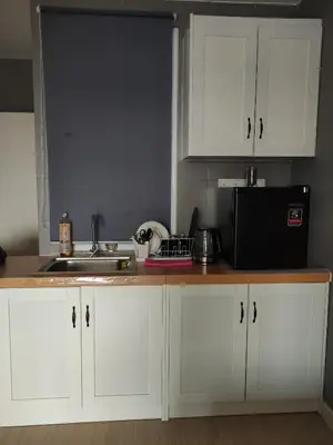 a kitchen with white cabinets and a sink and a microwave at Kampar Bonvoy Champs Elysees 4pax Homestay in Kampar
