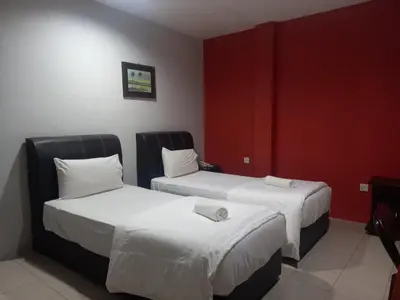 two beds in a hotel room with red walls at Reintree Lodge Hotel in Ipoh