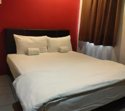 a bed with white sheets and pillows in a room at Reintree Lodge Hotel in Ipoh