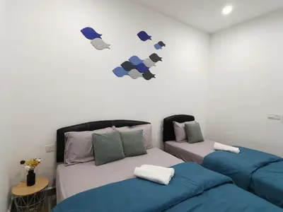 a room with two beds and a wall with a headboard at Octagon Ipoh Family Suites in Ipoh