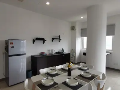 a white kitchen with a table and a refrigerator at Octagon Ipoh Family Suites in Ipoh
