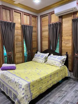 a bedroom with a bed with a yellow comforter at HOMESTAY DUSUN ANA BALUN in Slim River