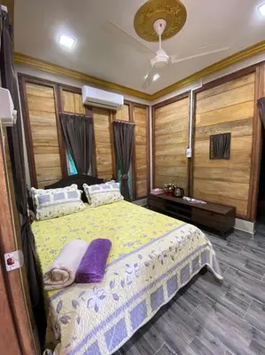 a bedroom with a large bed with purple pillows at HOMESTAY DUSUN ANA BALUN in Slim River