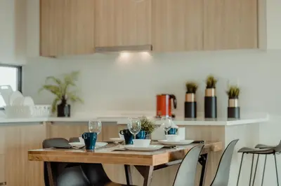 a kitchen with a wooden table with glasses and chairs at SOPHIA'S HOME - CITY and HILL VIEW 3BR at 218 Tropicana Macalister with Netflix & TV Box in George Town