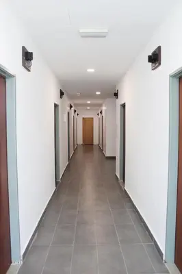 a hallway of an office building with white walls and a tile floor at Happy Valley Eco Farm in Kerling