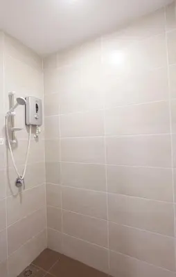 a shower in a bathroom with white tiles at CitiVilla Hotel Penang in George Town