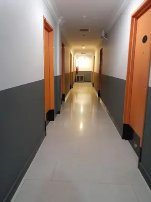 an empty hallway in an office building with orange doors at V HOTEL in Teluk Intan
