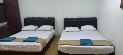 two beds in a small room with blue pillows at D'Mudah Motel & Homestay in Kulim