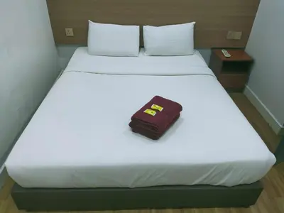 a suitcase sitting on top of a white bed at ESM Hotel in Tanah Rata