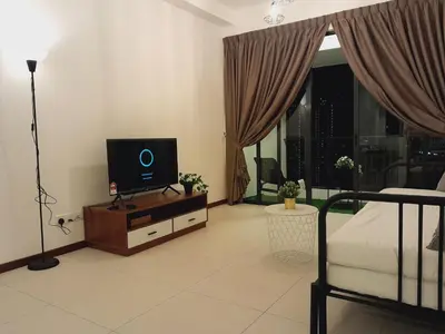 a living room with a bed and a tv on a table at The Landmark Comfort Relax Spacious Sea View By IZ in Tanjong Tokong