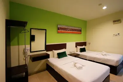 two beds in a room with green walls and a mirror at Golden Roof Hotel Falim Ipoh in Ipoh