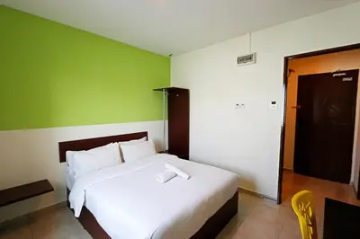 a bedroom with a white bed with a green wall at Golden Roof Hotel Falim Ipoh in Ipoh
