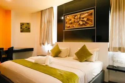 a bedroom with a large white bed with green pillows at Golden Roof Hotel Ampang Ipoh in Ipoh