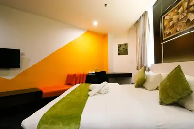 a hotel room with a large white bed with green sheets at Golden Roof Hotel Ampang Ipoh in Ipoh