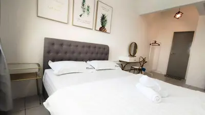 a bedroom with two beds with white sheets and a headboard at De Luma - Meritus in Perai